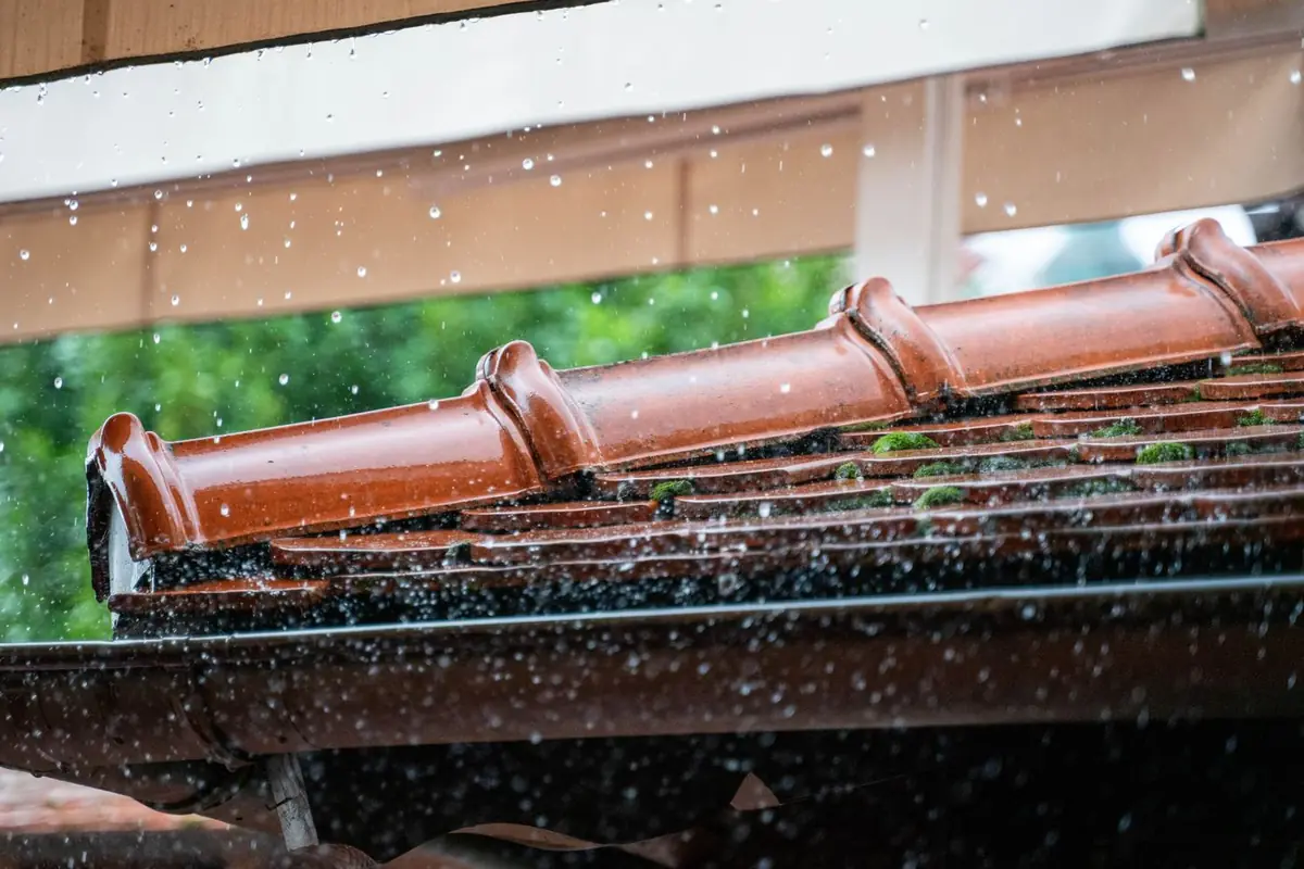 Rainwater dripping off the edge of a terracotta tile roof