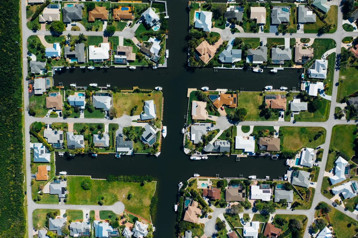 Aerial view of single-family homes with pools and green lawns along a grid of canals