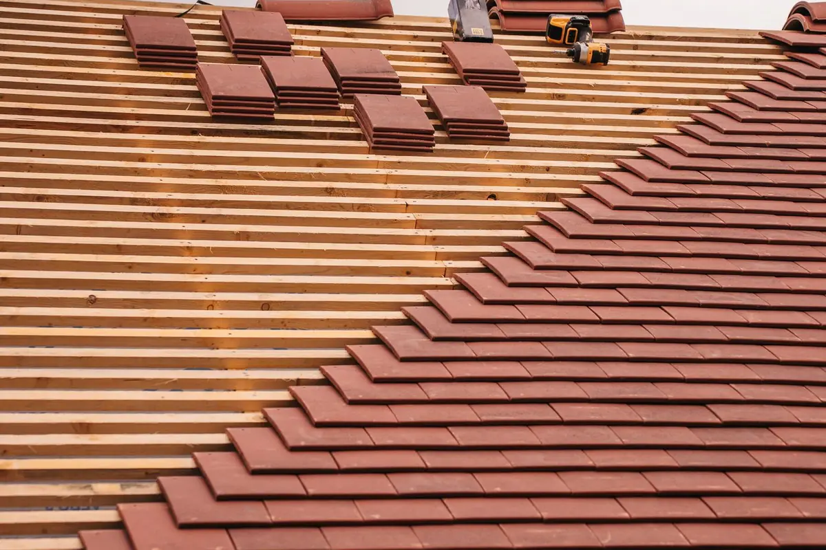 Rows of terracotta roof tiles with a few lifted and stacked during work on the roof